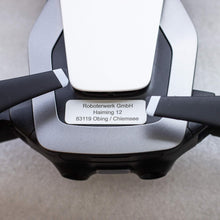 Laden Sie das Bild in den Galerie-Viewer, Drohnenkennzeichen 30×10 mm in Alu Silber mit gravierter Anschrift, auf einer weißen Drohne angebracht